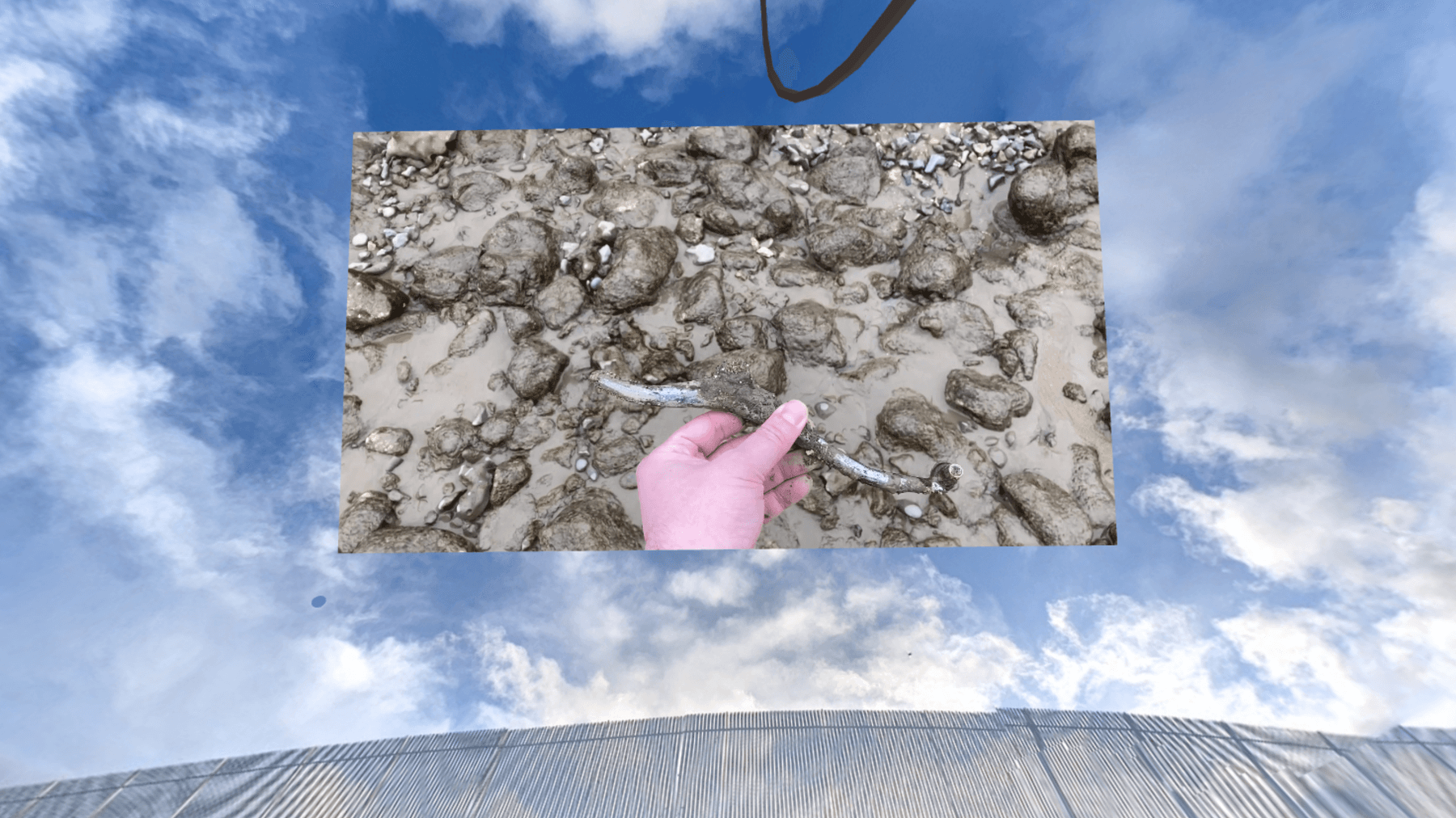 A screenshot taken inside the virtual exhibition environment. A video of the
object being discovered is projected onto a 360° photo of the thames
foreshore.