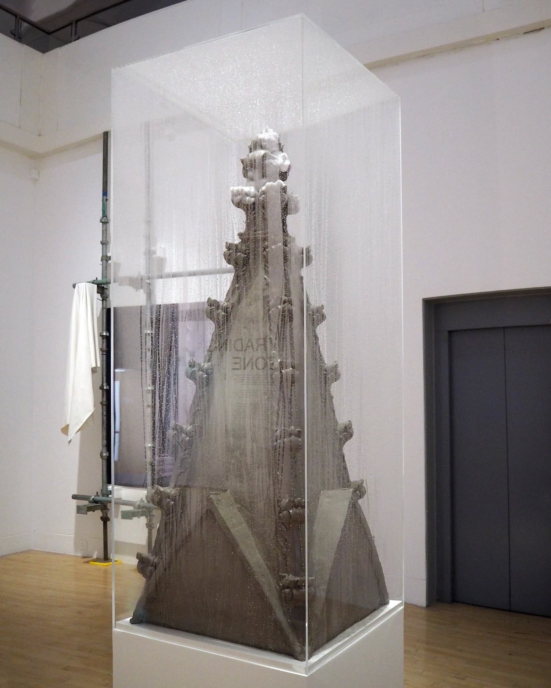A gothic pinnacle made from clay in a foggy, perspex
vitrine.