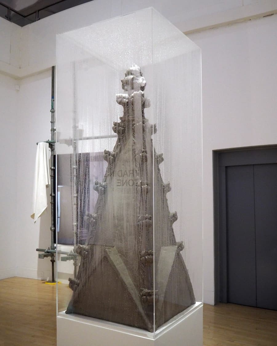 A gothic pinnacle made from clay in a foggy, perspex
vitrine.