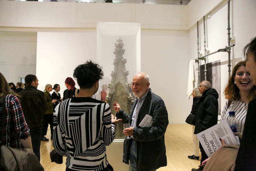 A group of people stand around the sculpture at the gallery opening
event.
