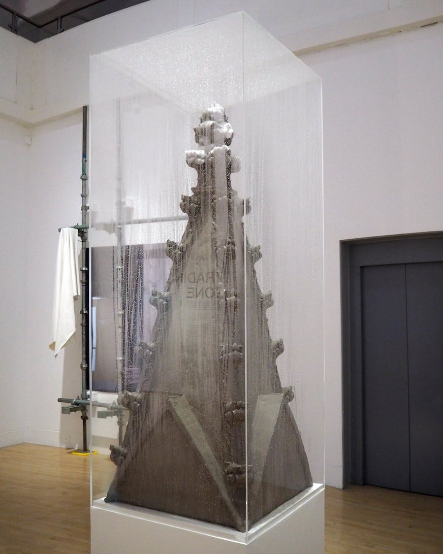 A gothic pinnacle made from clay in a foggy, perspex
vitrine.